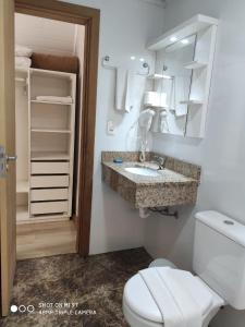 uma casa de banho com um WC, um lavatório e um espelho. em Hotel Cabana Jardim de Flores em Gramado