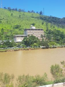 a large building on a hill next to a river at Flat Hotel Cavalinho Branco in Águas de Lindóia