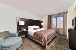 Staybridge Suites O'Fallon Chesterfield, an IHG Hotel في أوفالون: غرفه فندقيه بسرير وكرسي