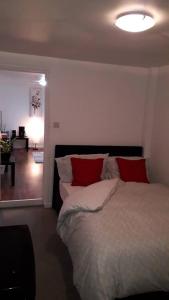 a bedroom with a large bed with red pillows at Cosy London holiday Home (Near O2 arena) in London