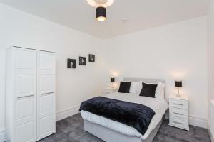 ein weißes Schlafzimmer mit einem Bett und zwei Nachttischen in der Unterkunft Cherry Property - Berry Apartments in Blackpool