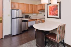 a kitchen with a table and a refrigerator at Staybridge Suites O'Fallon Chesterfield, an IHG Hotel in O'Fallon