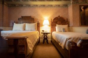 a bedroom with two beds and a table with a lamp at The Strater Hotel in Durango