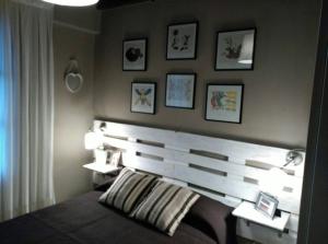 1 dormitorio con cabecero de madera y cuadros en la pared en Las endrinas, en Llanes