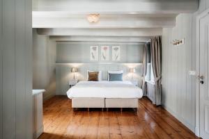 a bedroom with a white bed and wood floors at Logement Petit Beijers in Utrecht