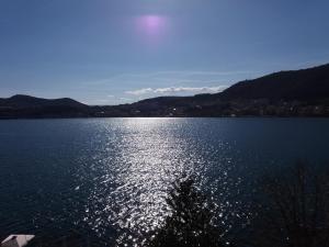 a large lake with the sun reflecting on the water at Kastoria apartment μπροστά στη λίμνη στο κέντρο in Kastoria