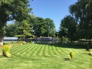 a park with a large grass field and a lake at River Nene Cottages in Water Newton