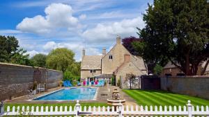 a house with a swimming pool and a white fence at River Nene Cottages in Water Newton