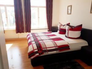 Schlafzimmer mit einem Bett mit roten und weißen Kissen in der Unterkunft Pension Altenburg City in Altenburg