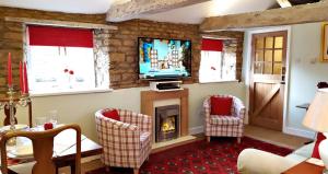 a living room with a fireplace and a tv at River Nene Cottages in Water Newton