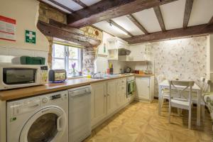 a kitchen with a washing machine and a microwave at River Nene Cottages in Water Newton