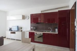 kuchnia z czerwonymi szafkami i zlewem w obiekcie Apartment Victoria, cozy studio flat near Leonardo Academy w mieście Sesto Calende +7 zdjęć