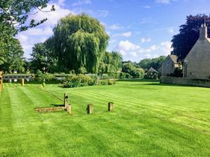 a large grass field with a house in the background at River Nene Cottages in Water Newton