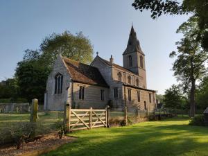 an old church with a fence in the grass at River Nene Cottages in Water Newton