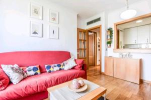 ein rotes Sofa im Wohnzimmer mit einem Tisch in der Unterkunft Apartamento 4 pax Airport Wanda Ifema WiFi in Madrid