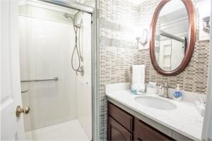 ein Bad mit einer Dusche, einem Waschbecken und einem Spiegel in der Unterkunft 309 Water Street Inn in Boyne City