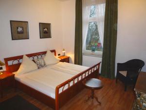 a bedroom with a bed and a chair and a window at Hotel Alt-Lennep in Remscheid