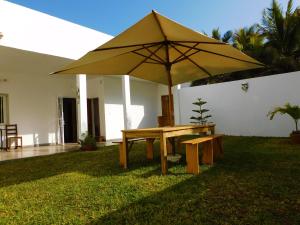 una mesa de picnic con una sombrilla en un patio en Villa Ty Milyn Mazela SA en Dakar