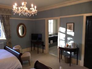 a bedroom with a bed and a desk and a chandelier at Gellihaf House in Blackwood