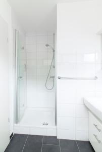 La salle de bains blanche est pourvue d'une douche et d'un lavabo. dans l'établissement Quiet Nature Near Cologne 1, à Bergisch Gladbach