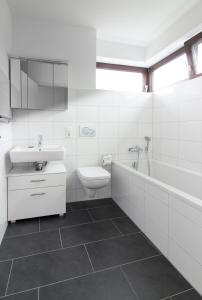 La salle de bains blanche est pourvue d'un lavabo et de toilettes. dans l'établissement Quiet Nature Near Cologne 1, à Bergisch Gladbach