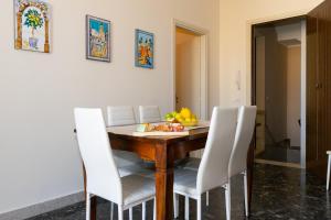 tavolo da pranzo con sedie bianche e cesto di frutta di Il Mosaico Family Apartments a Mazara del Vallo