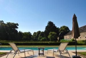 - deux chaises, une table et un parasol à côté de la piscine dans l'établissement Chateau La Touanne Loire valley, à Baccon