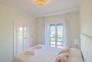 a white bedroom with a bed and a window at Pool & Tennis Beach House in Praia da Barra +38 photos