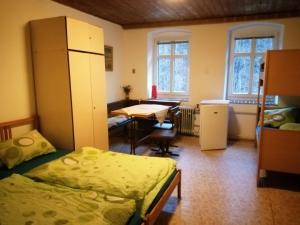 a room with two beds and a table and a desk at Chata Pepino in Ludvíkov