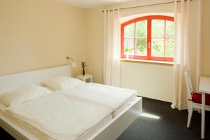 a white bedroom with a bed and a window at Kulturgasthof Alte Reederei in Fürstenberg-Havel
