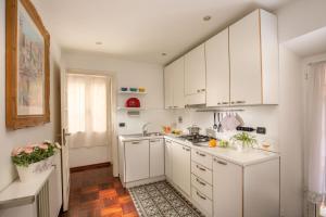 a white kitchen with white cabinets and a sink at Riccardo Condotti Suite in Rome