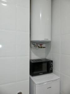 a kitchen with a black microwave and a white cabinet at APARTAMENT Encantador al Centre de Vic APTGARBI in Vic