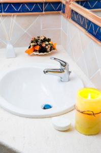 een wastafel in de badkamer met een kaars en een kaars bij Hotel Baja Romantica in Bosa