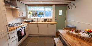 a kitchen with white cabinets and a wooden table at Moreton Cottage in Moreton in Marsh