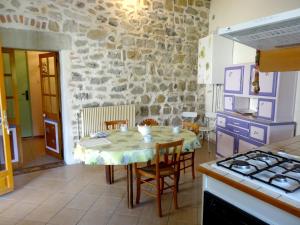 uma cozinha com uma mesa com cadeiras e uma parede de pedra em Gites les Eaux Claires em Saint-Paul-le-Jeune