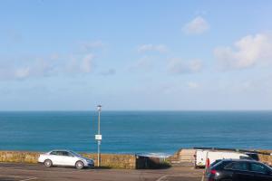 two cars parked in a parking lot next to the ocean at SeaCrest 1 in St Ives