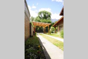 a garden with a wooden pergola next to a building at La Aljaba in El Bolsón