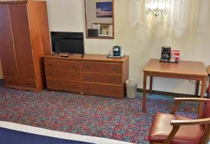 a room with a dresser and a tv and a desk at Cedar Motor Inn in Marquette