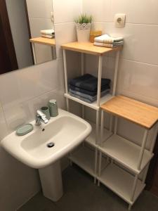 a bathroom with a white sink and shelves at Apartments Dara in Rogoznica