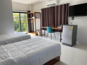 a bedroom with a bed and a desk and a television at DD Modern House in Surat Thani