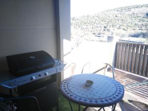 a patio with a table and a grill on a balcony at El Cerrillo II in San Martín del Pimpollar