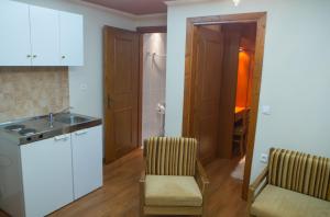 a kitchen with white cabinets and a sink and chairs at Exohiko in Palaios Agios Athanasios