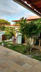a yard with trees and a house with a patio at Casa a 3 minutos da praia in Saquarema