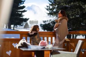 een vrouw en een klein meisje die naast een hek staan bij Hôtel Chalet Mounier in Les Deux Alpes