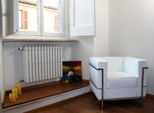 une chaise blanche assise sous une fenêtre à côté d'un radiateur dans l'établissement Via Giotto, 5, à Assise