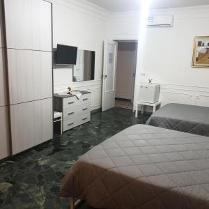 ein Schlafzimmer mit einem Bett, einem Schreibtisch und einem Fernseher in der Unterkunft B&B GANAJ - Corso Italia 89 - BARI in Bari