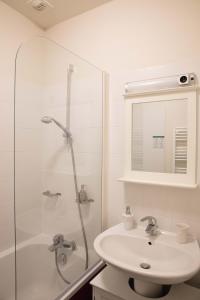 a white bathroom with a sink and a shower at Appartement A-Mi-Chemin - Centre-ville de Tournus in Tournus