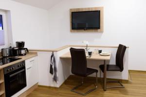 a kitchen with a table and chairs and a tv on the wall at Ferienwohnung am Westerturm in Duderstadt