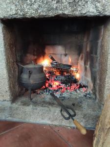 um grande forno de pedra com panela e fogo em Casa da Boa Vista em Viadal em Vale de Cambra