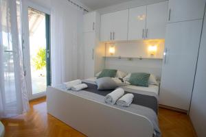 a white bedroom with two beds and a large window at VILLA MILENKA - Apartmani Gorana in Tučepi